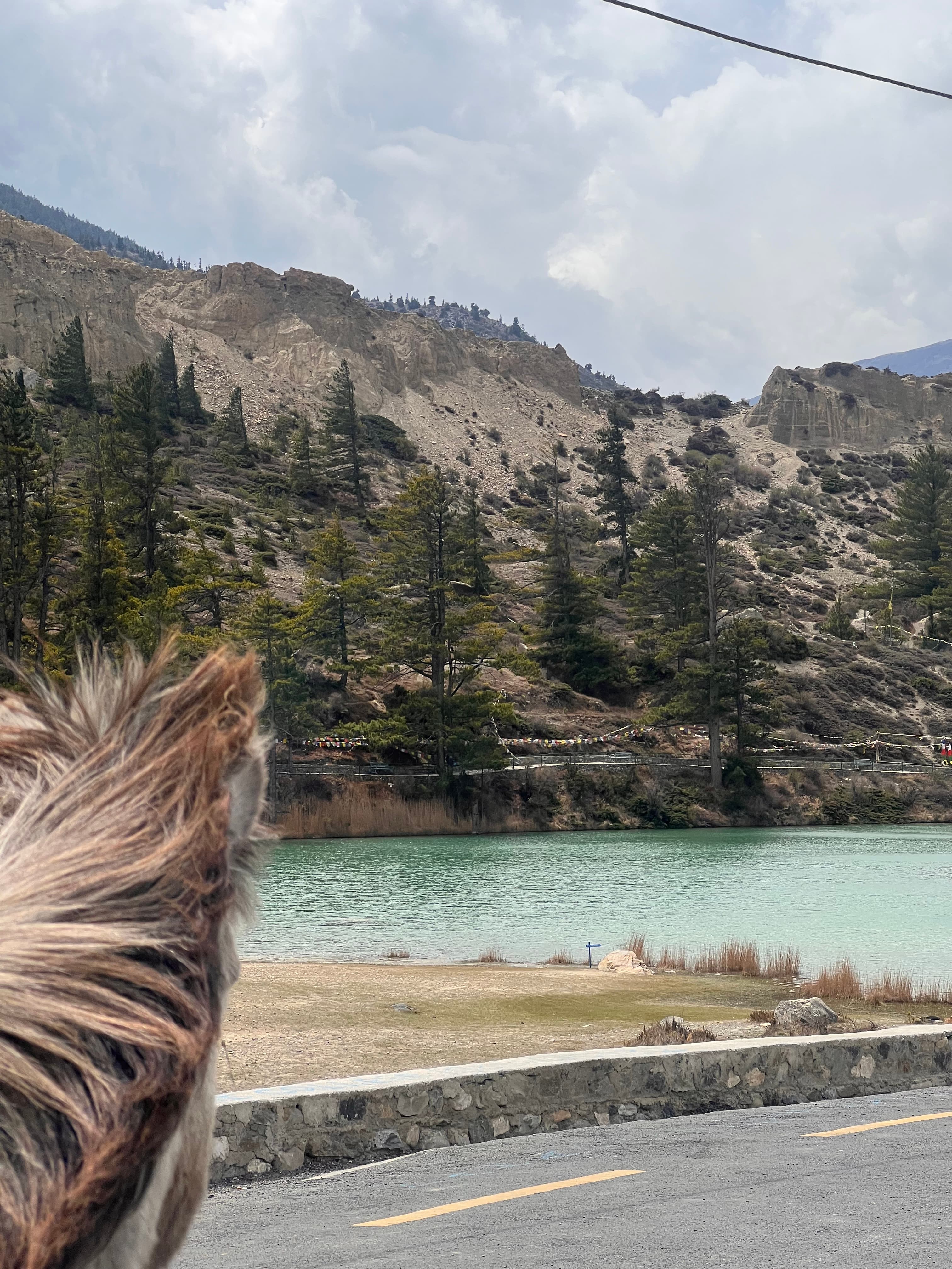 Turquoise lake on the road to Mustang, prayer flags in the distance